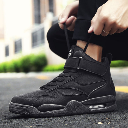 Person wearing a black high-top sneaker on an outdoor street background