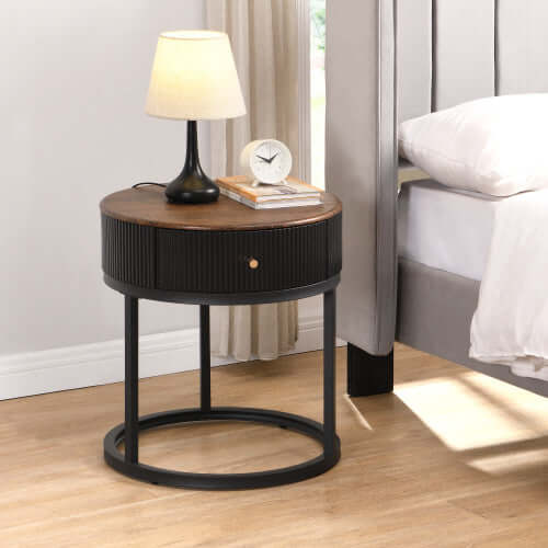 Small space round table with drawers next to a bed, featuring a lamp and clock for stylish bedroom organization.