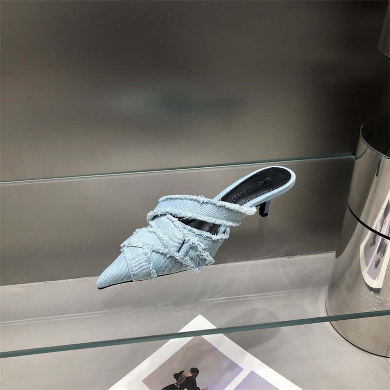 Light blue women's kitten heel sandals with stylish crisscross straps showcased on a display shelf.