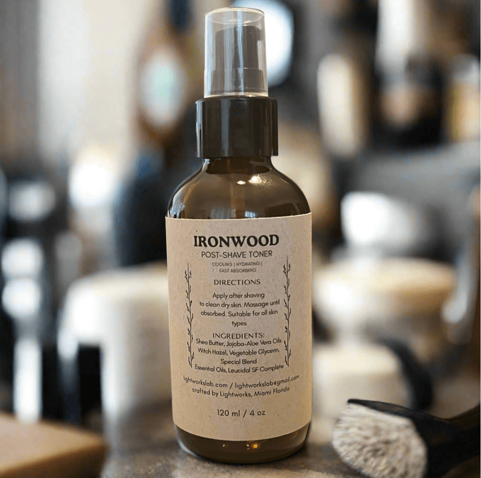 Bottle of Ironwood post-shave toner on a blurred barbershop background