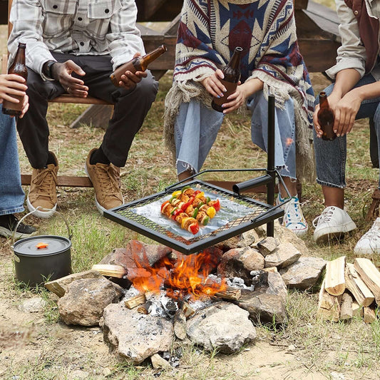 Group enjoying food on a swivel fire pit grill over a campfire, perfect for outdoor BBQs and grilling.