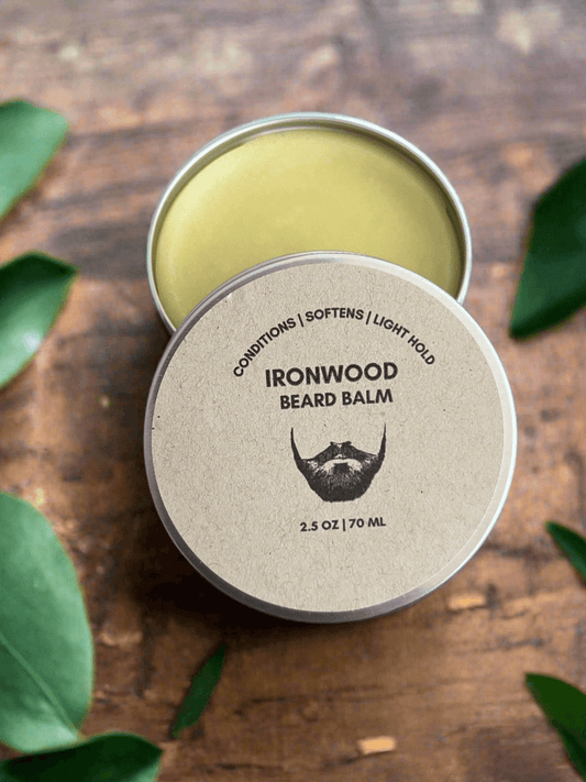 Ironwood beard balm in a metal tin on a wooden surface with leaves around