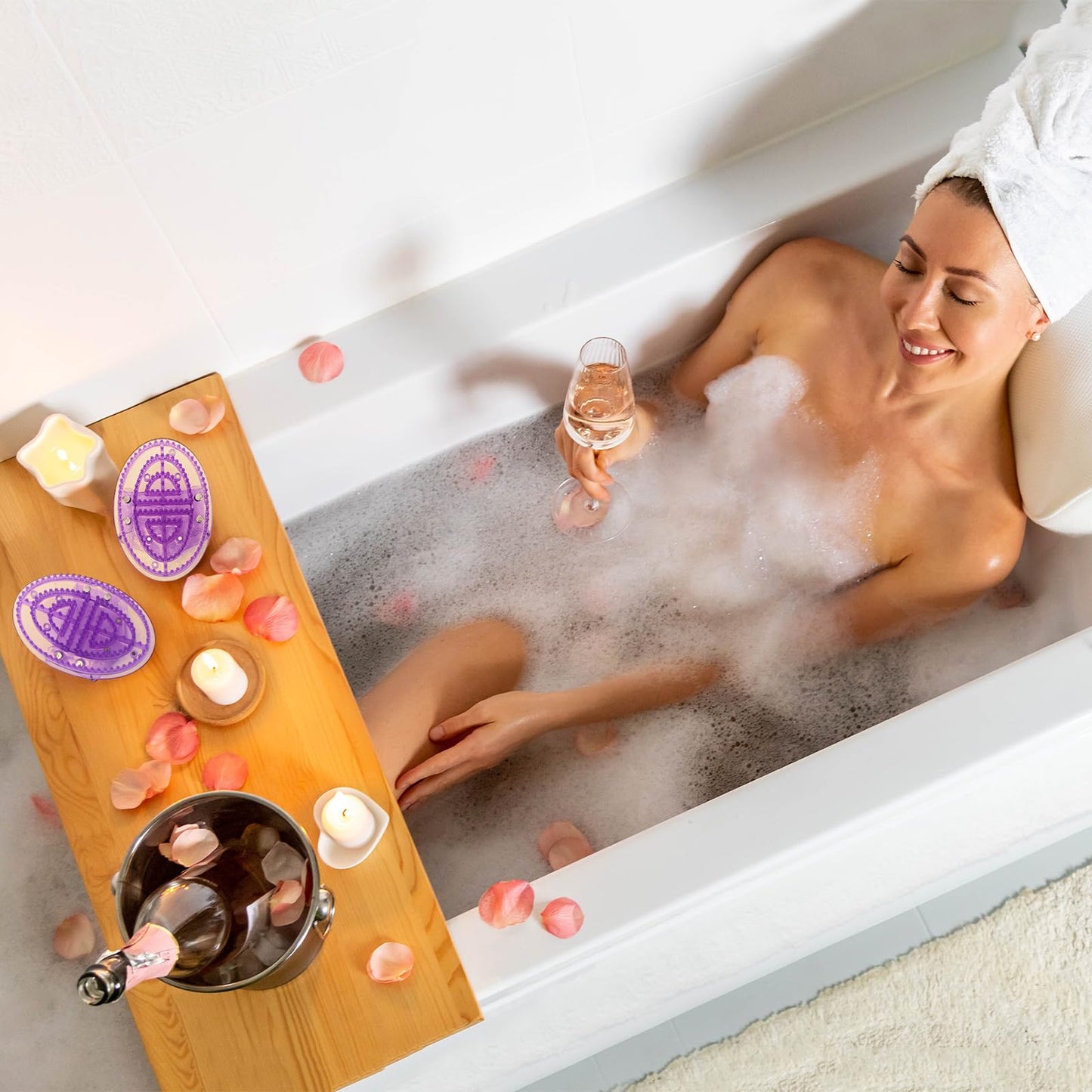 Woman in a bubble bath with a glass of champagne, surrounded by candles and rose petals.