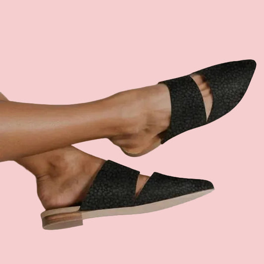 Black woven flat shoes worn by a person on a light pink background