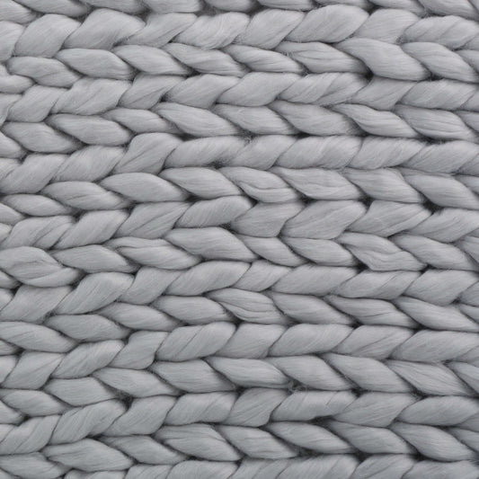 Close-up of a luxurious light gray knitted blanket showcasing intricate woven texture.