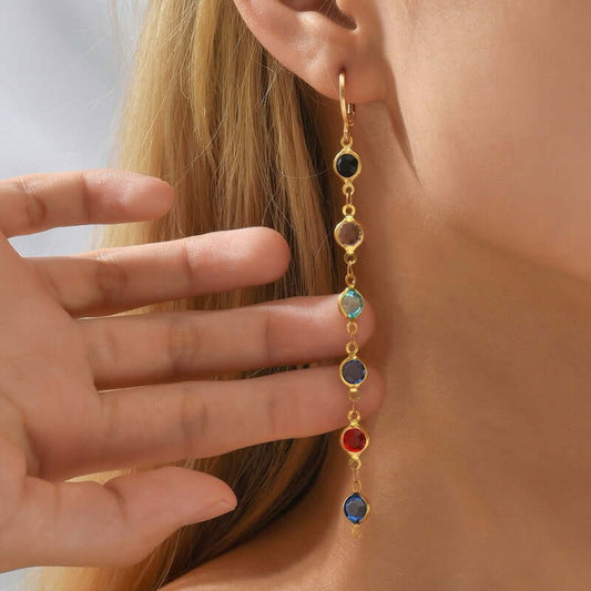 Close-up of a person wearing a colorful gemstone earring with gold detailing.