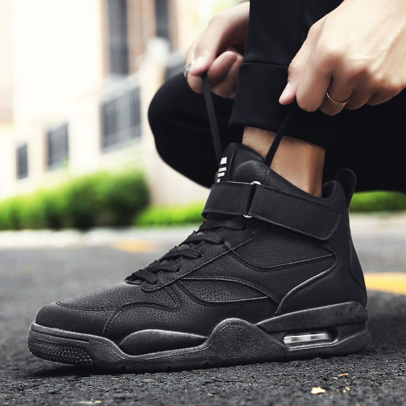 Person wearing a black high-top sneaker on an outdoor street background