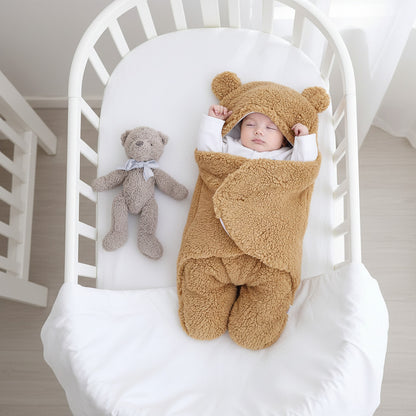 Baby in a brown bear-themed sleeping bag with a teddy bear on a white background