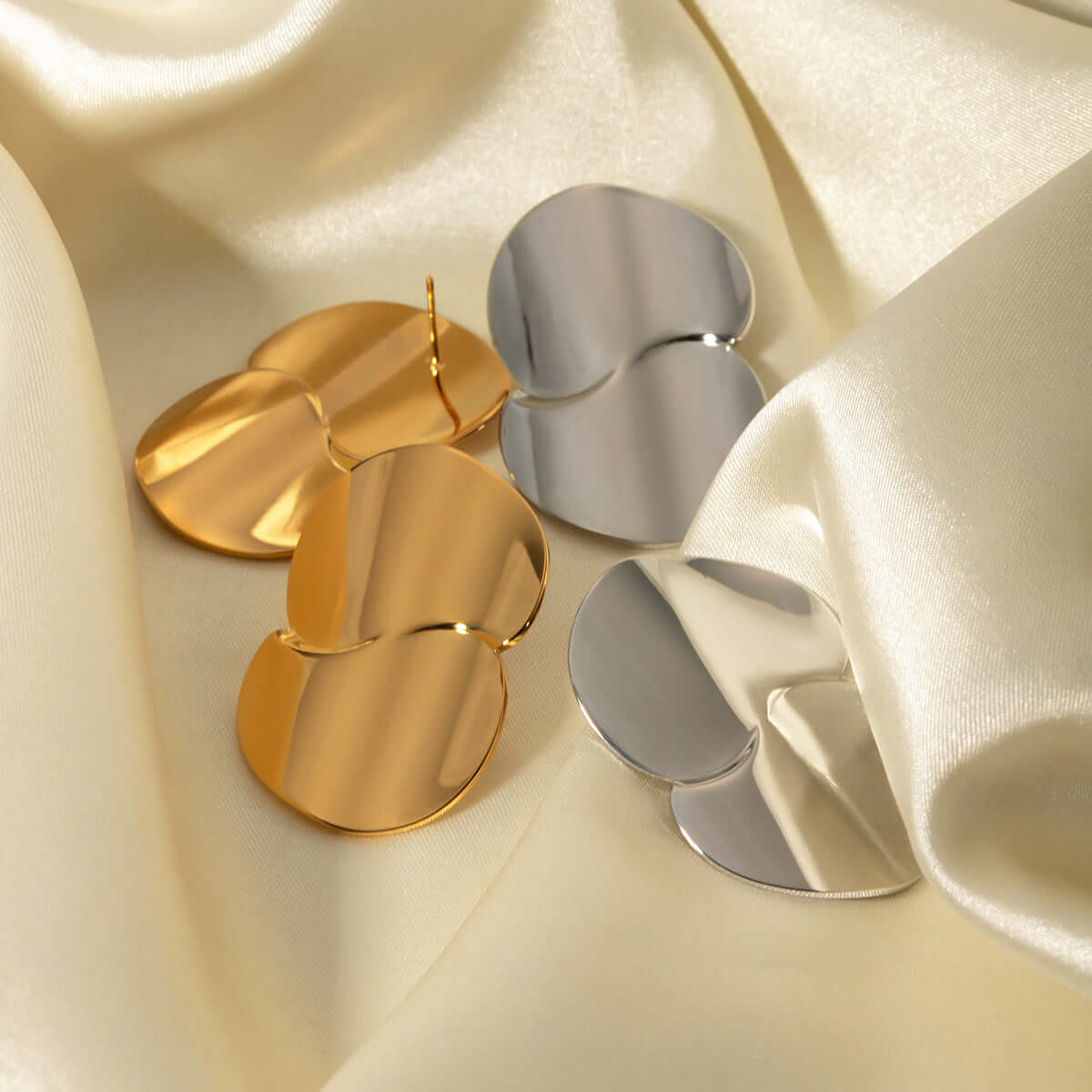 Stainless Steel Minimalist Geometric Curve Earrings displayed in gold and silver against soft fabric.