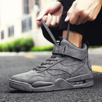 Person tying a gray high-top sneaker on an outdoor street background