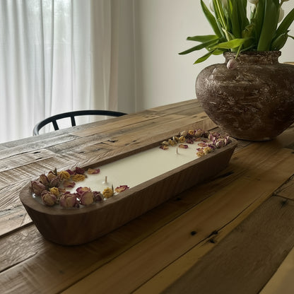 Wooden table with a rustic candle holder and vase of tulips in a home setting.