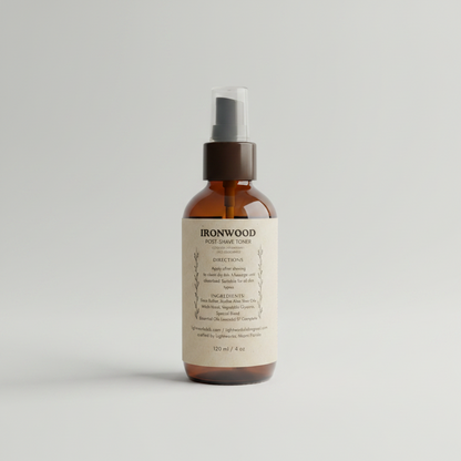 Bottle of Ironwood post-shave toner on a blurred barbershop background