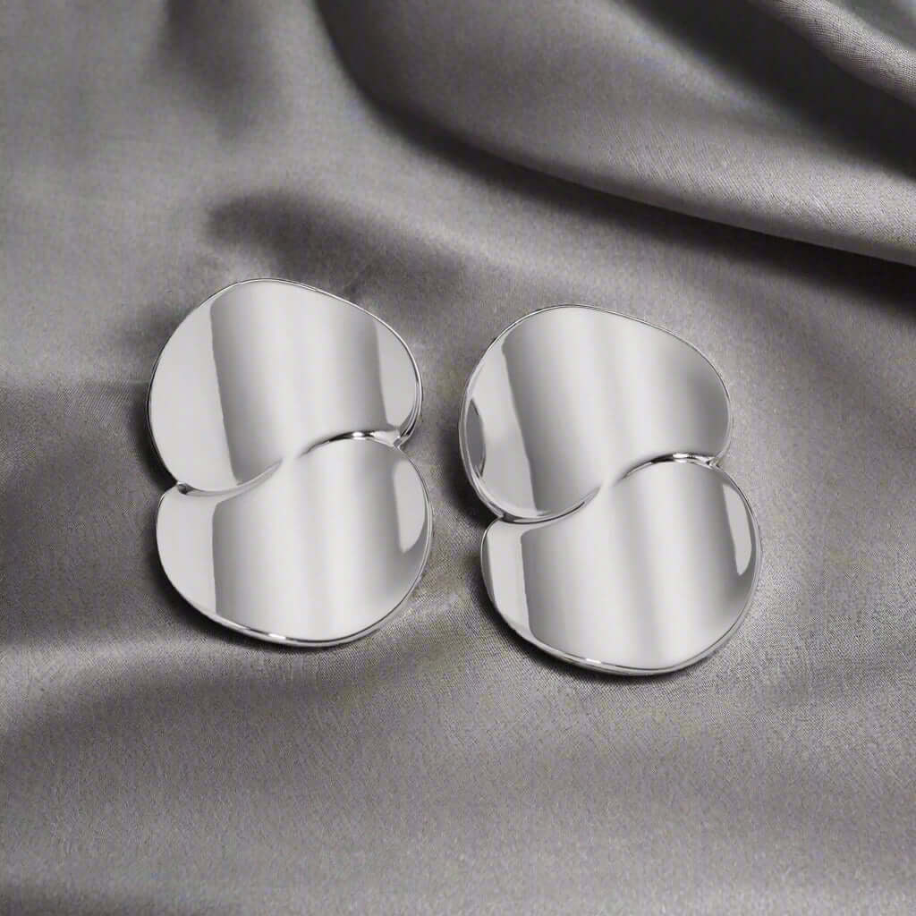Stainless Steel Minimalist Geometric Curve Earrings on a silky gray background, reflecting contemporary elegance.