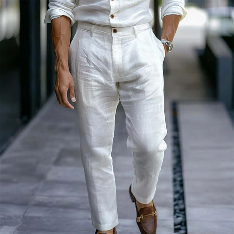 Person wearing a white outfit with white pants and brown shoes on a blurred street background