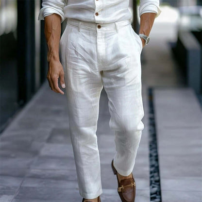 Person wearing a white outfit with white pants and brown shoes on a blurred street background