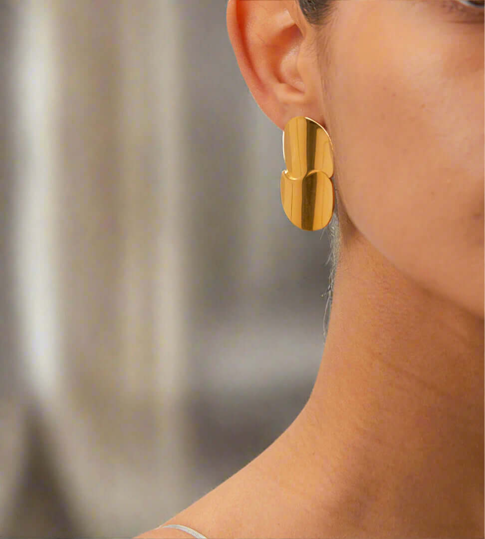 Stainless Steel Minimalist Geometric Curve Earrings worn by a model showcasing their elegant gold glow and contemporary design.
