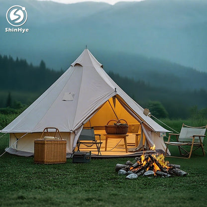 Camping scene with a tent, chairs, and fire pit in a mountainous area, featuring ShinHye logo.