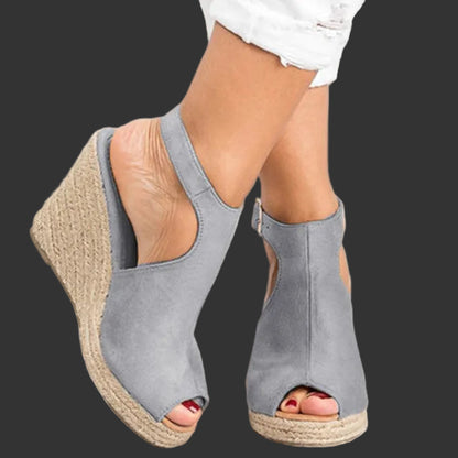 Gray wedge sandals with open toes on a light wooden floor.
