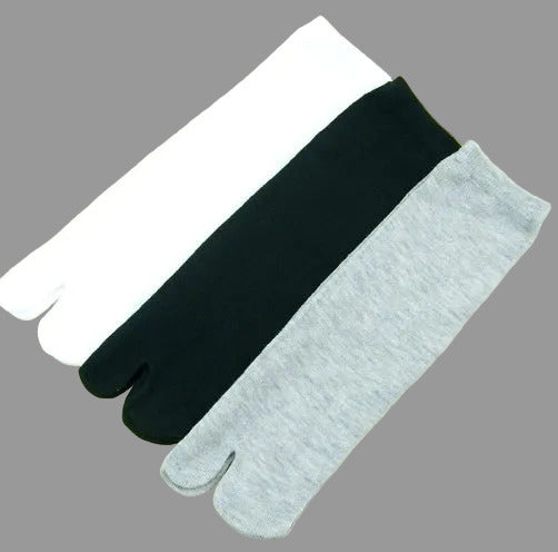 Three pairs of split-toe socks in white, black, and gray on a beige background