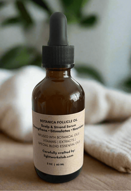 Botanica Follicle Oil bottle with dropper on a wooden surface with a blurred green plant background