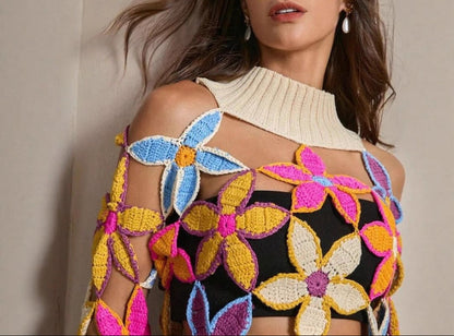 Woman wearing a colorful floral crochet top against a neutral background
