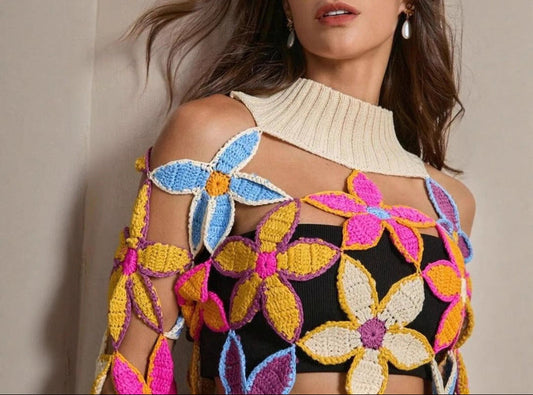 Woman wearing a colorful floral crochet top against a neutral background