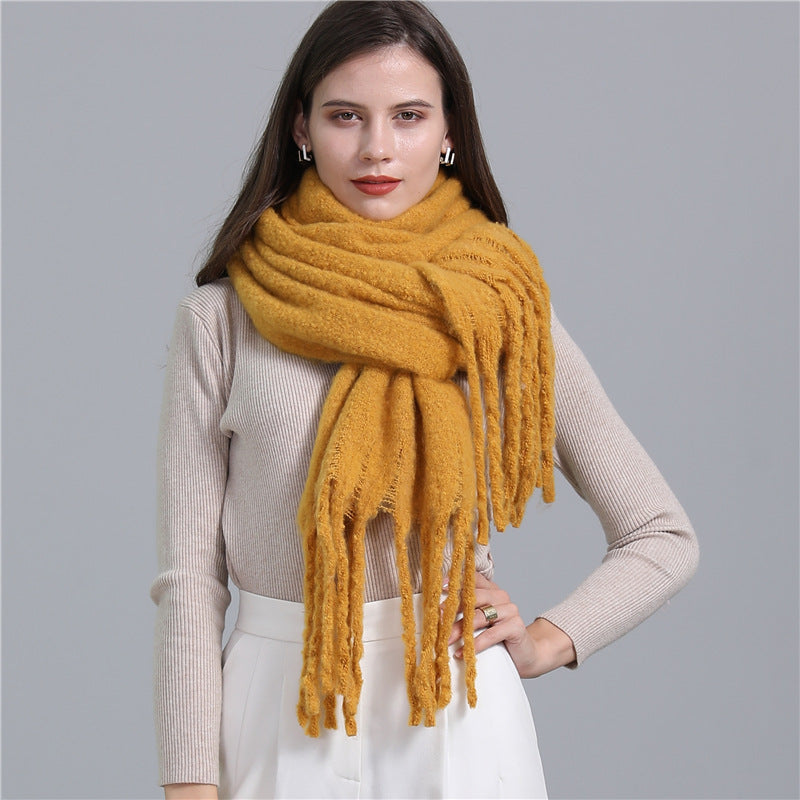 Woman wearing a mustard yellow scarf against a gray background