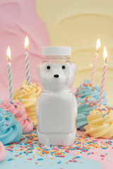 Kids Powdered Bubble Bath | Gentle Fizzy Bath Soak in a bear-shaped bottle surrounded by colorful cupcakes and candles.