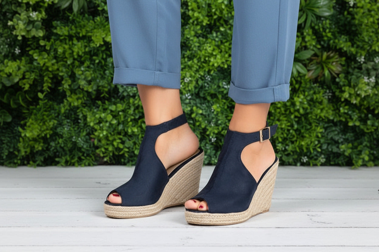 Navy wedge sandals with jute sole on a white wooden floor