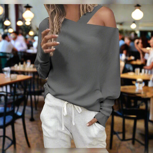 Person wearing a gray off-shoulder top and light gray sweatpants in a restaurant setting